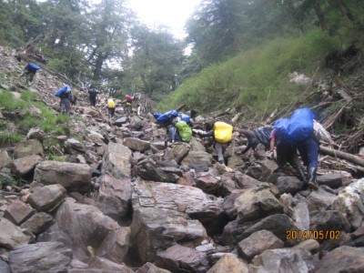 護管員背負重裝在陡峭地形前進